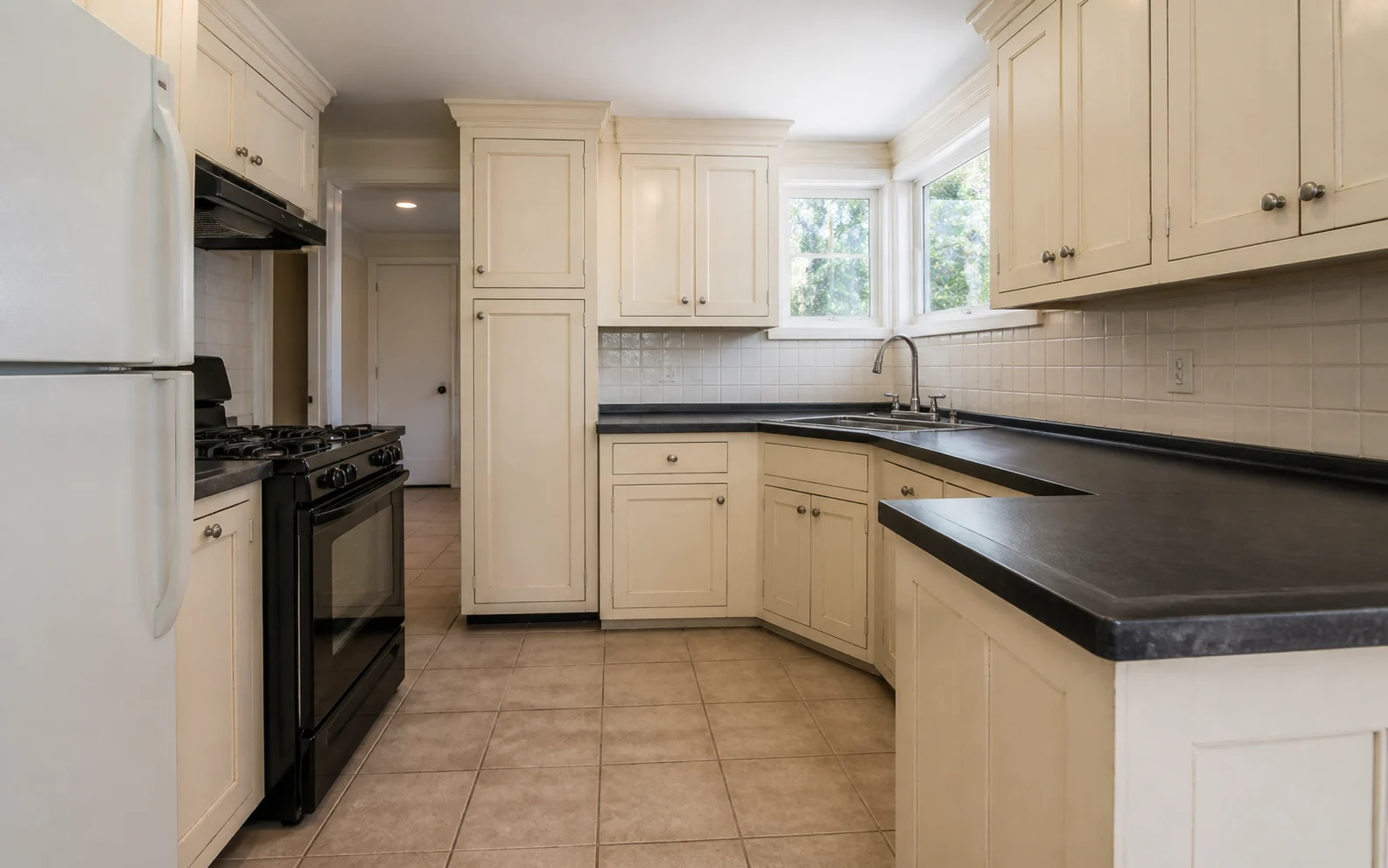 The original L-shaped kitchen with aged ivory painted cabinets